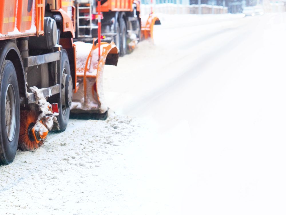 Mechanized snow removal. Blurred winter background. Snow plough truck clearing road after blizzard.