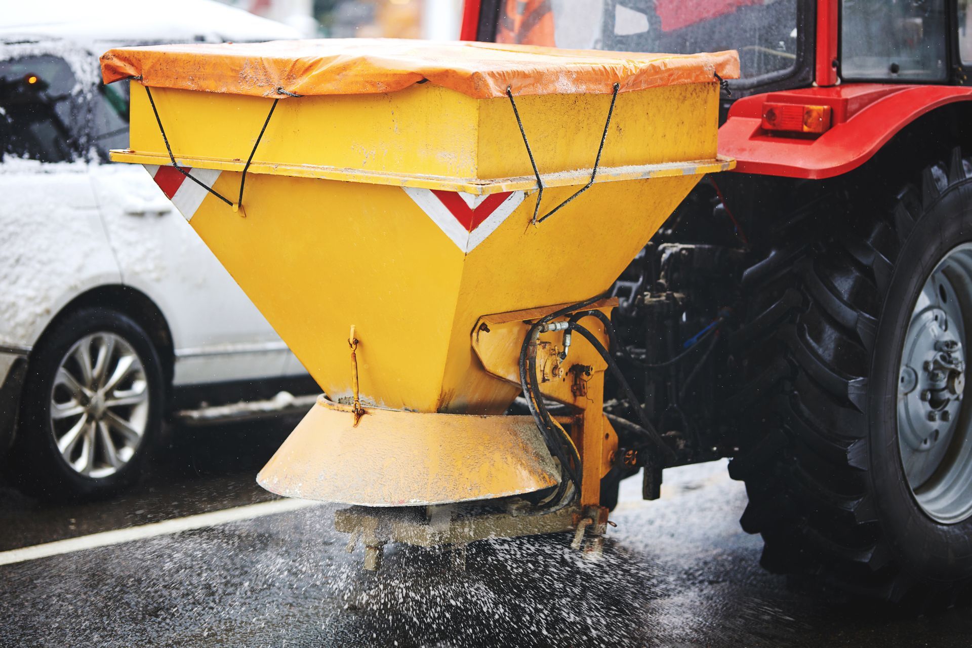 An ice salter spraying a retail shop sidewalk.