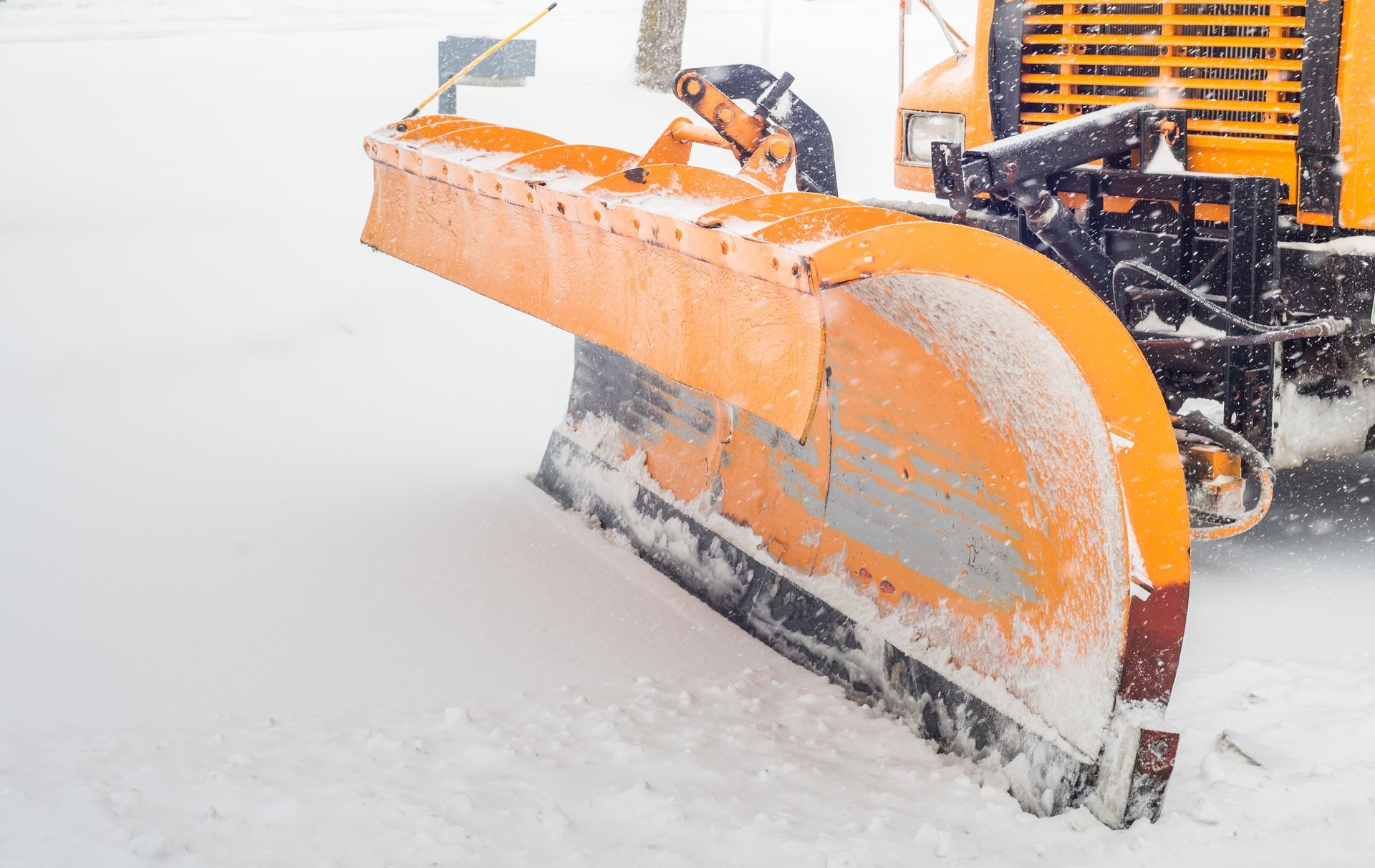 A snow plow is plowing snow on a snowy road.