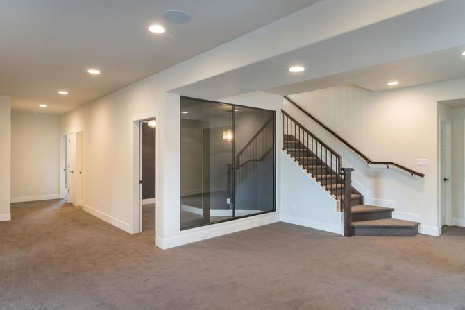 An empty basement with stairs and a glass wall.
