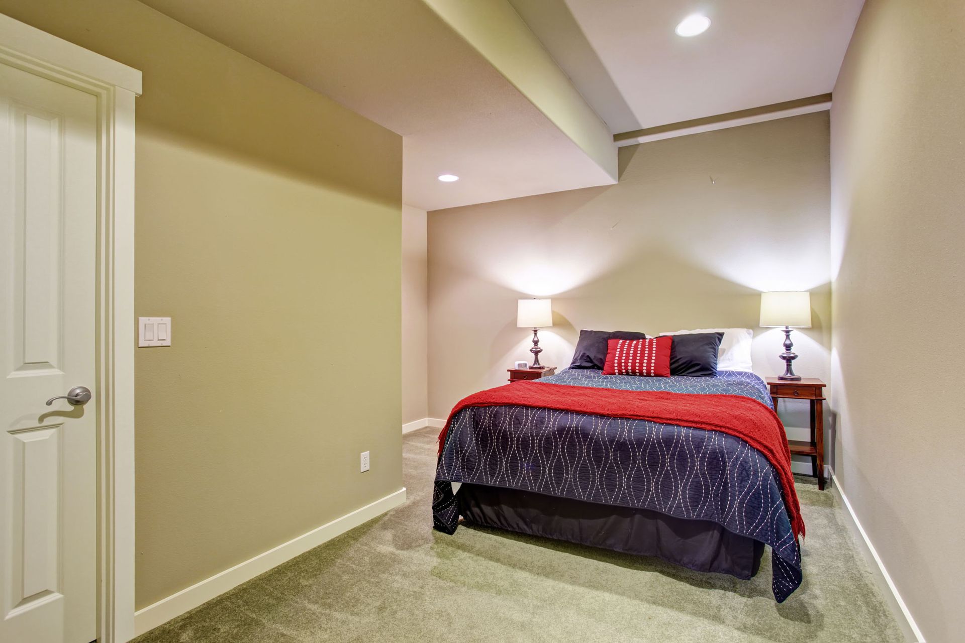 A bedroom in a basement with a bed and a door.