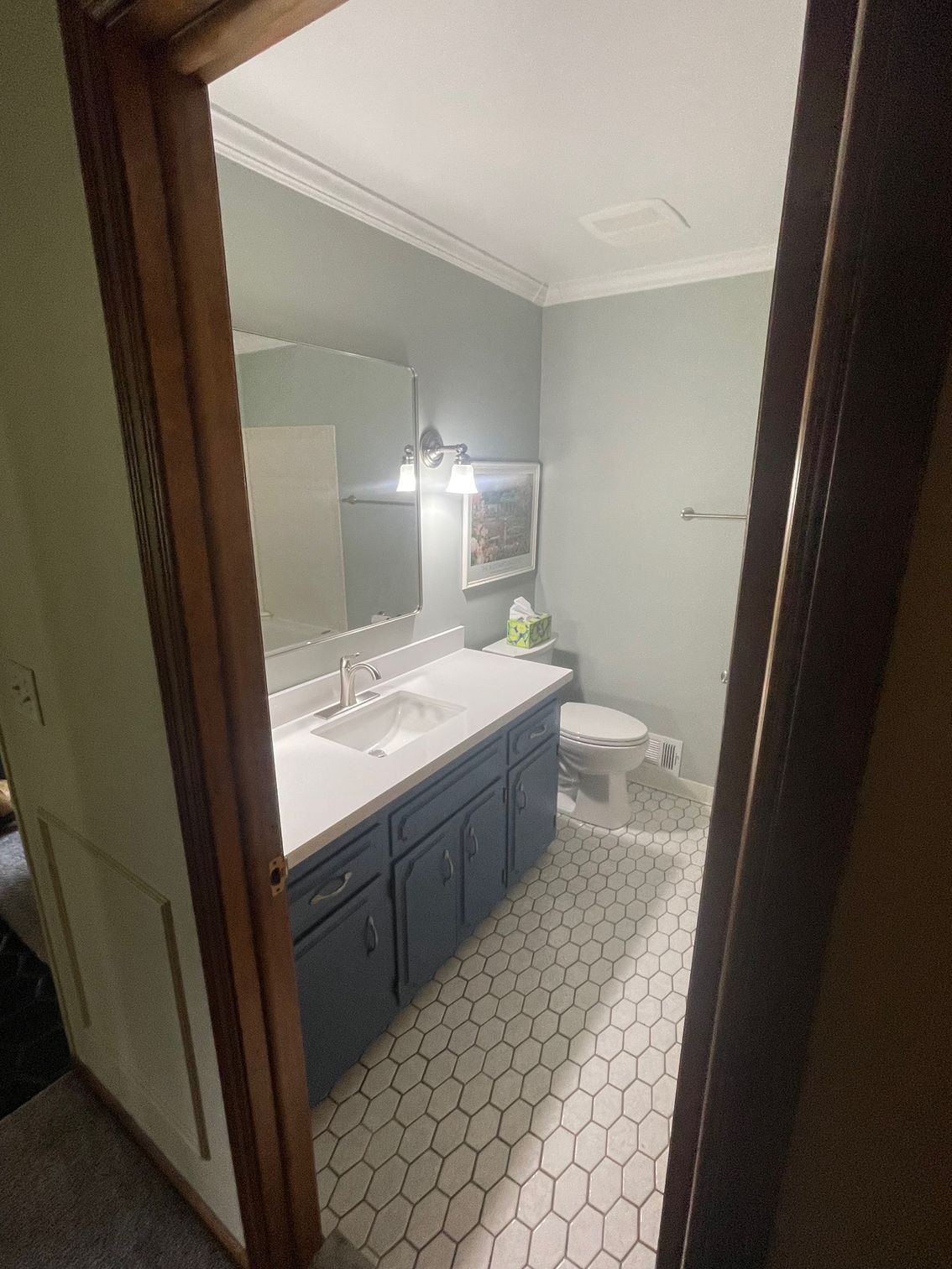 Bathroom with blue cabinets, white countertop, and hexagonal floor tiles.