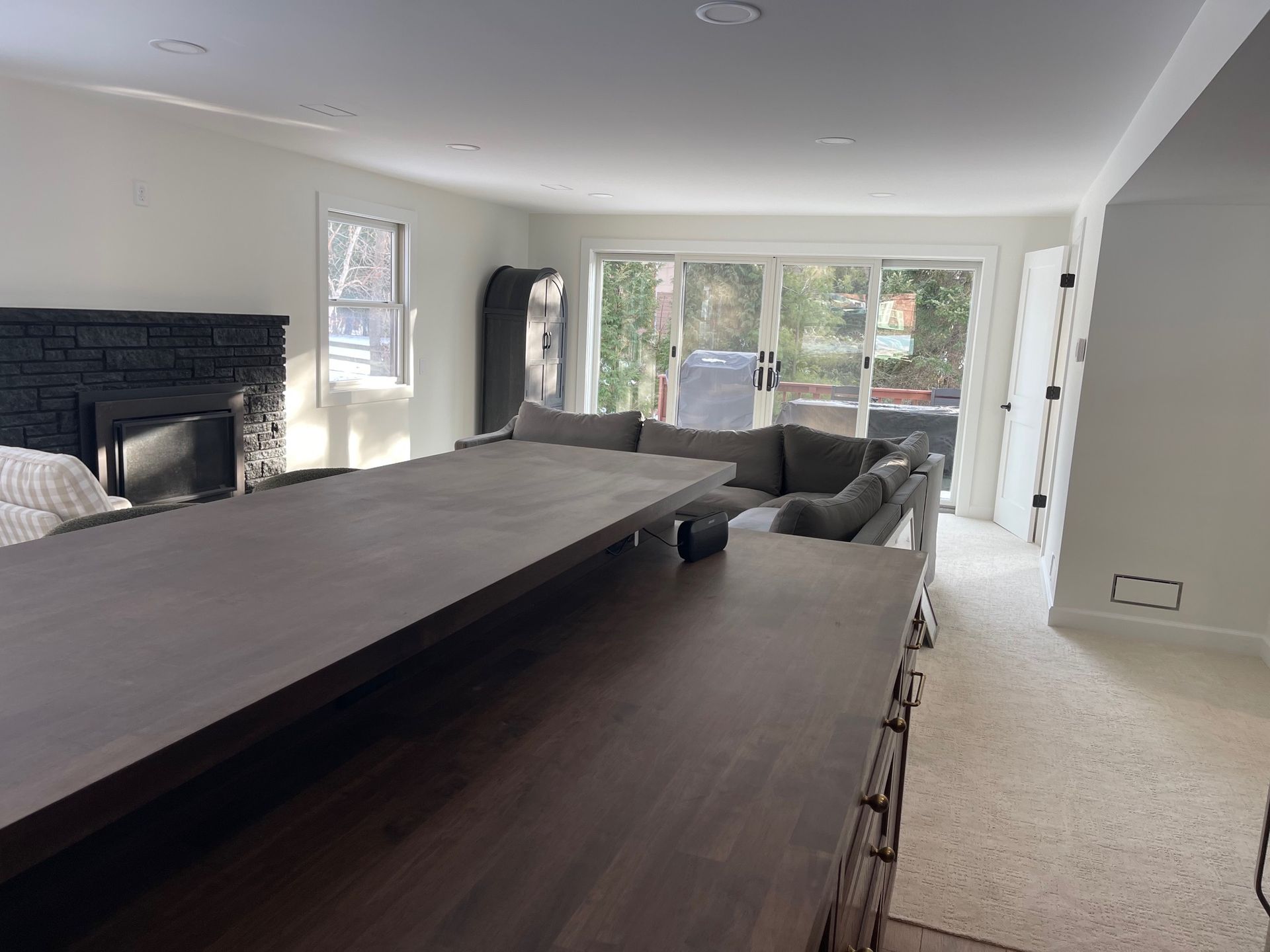 Spacious living room with a long wooden island, sectional sofa, fireplace, and sliding glass door to a patio.