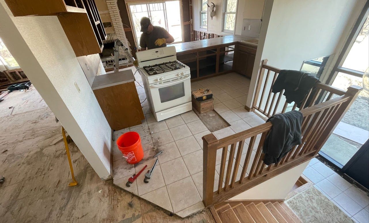A man is working on a stove in a kitchen.