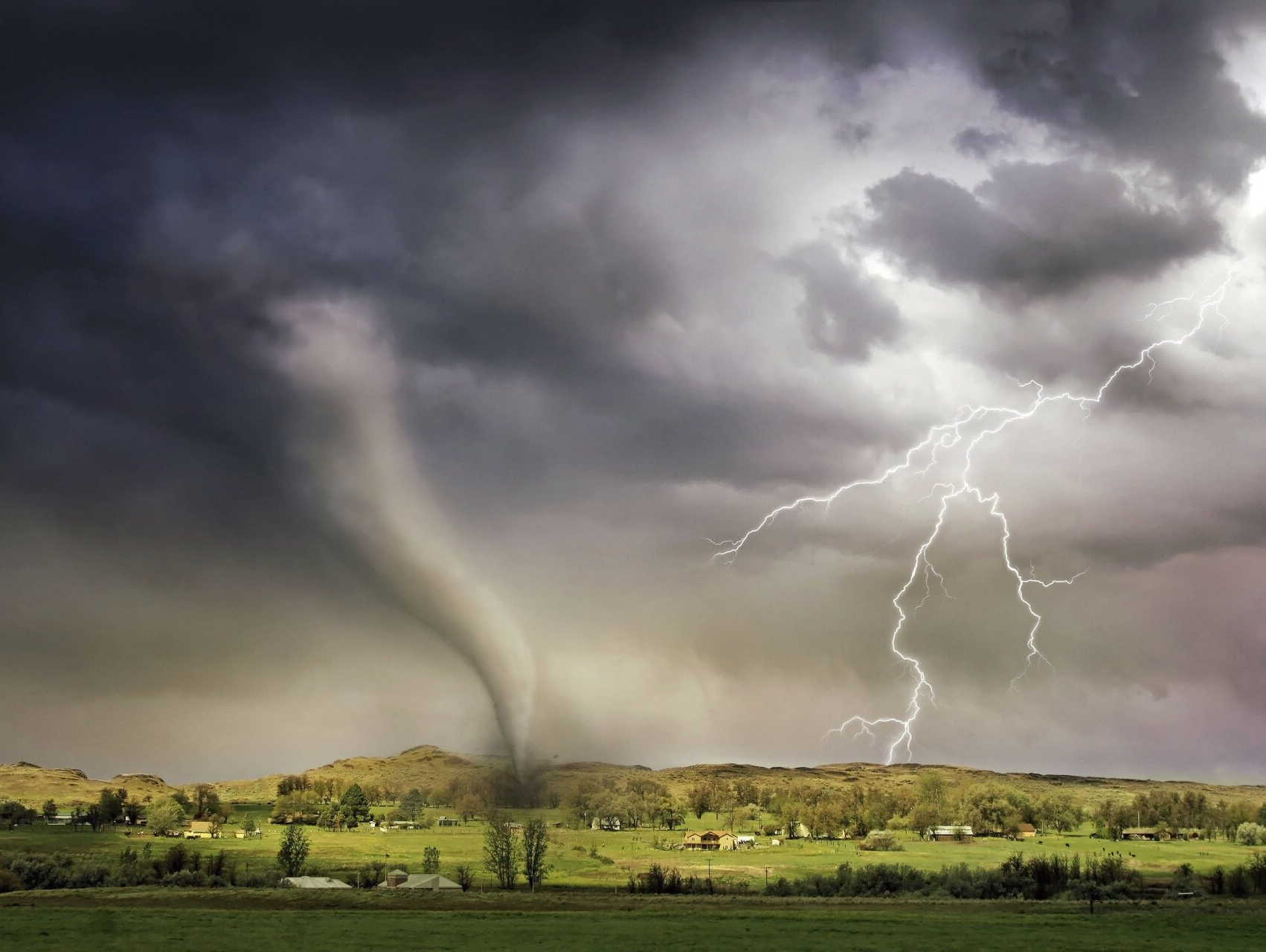 There is a tornado and lightning in the sky.