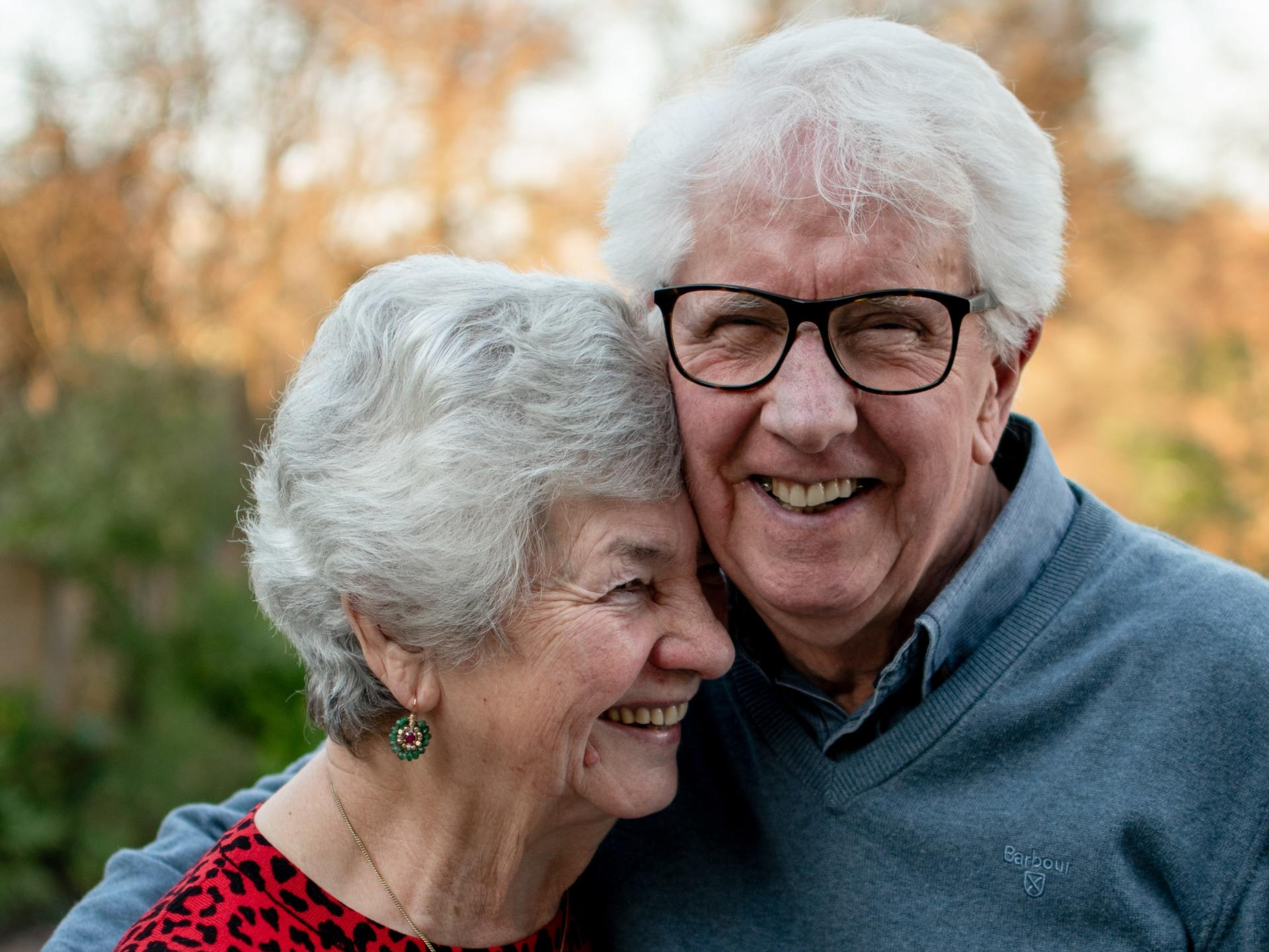 A man and a woman are hugging each other and smiling for the camera.