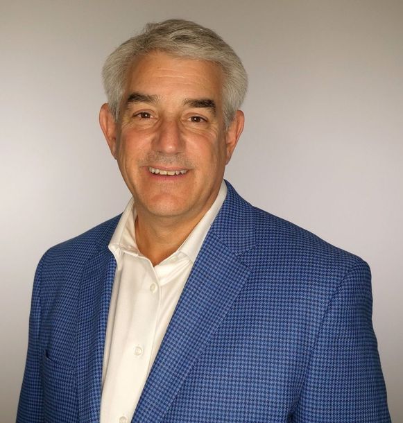 A man in a suit and tie is smiling for the camera