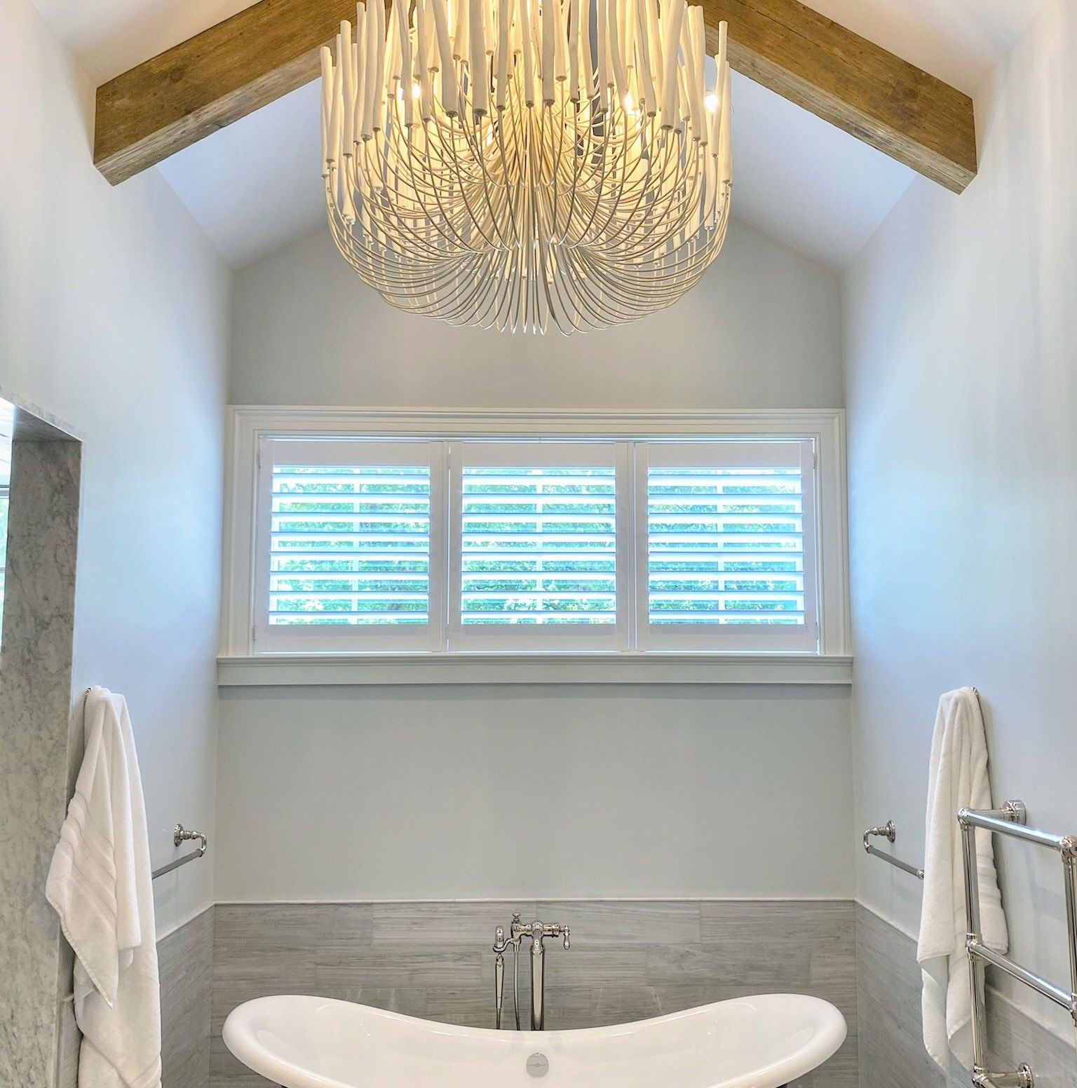 A bathroom with a tub and a chandelier hanging from the ceiling