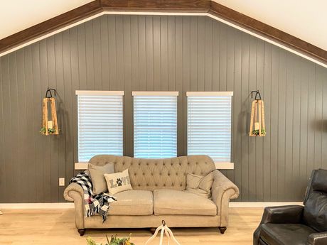 A living room with a couch , chair , and vaulted ceiling.