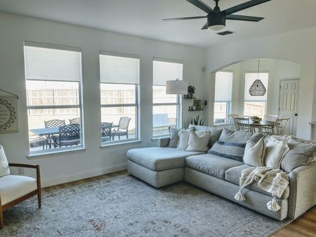 A living room with a sectional couch and a ceiling fan.
