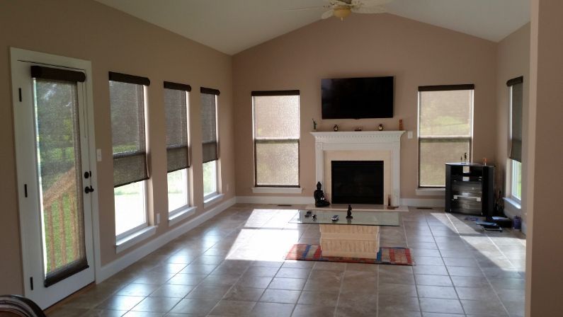 A living room with a fireplace and a flat screen tv and eco-friendly window coverings. Love is Blinds