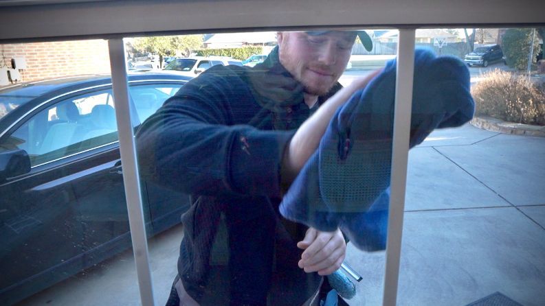 A man is cleaning a window with a towel.