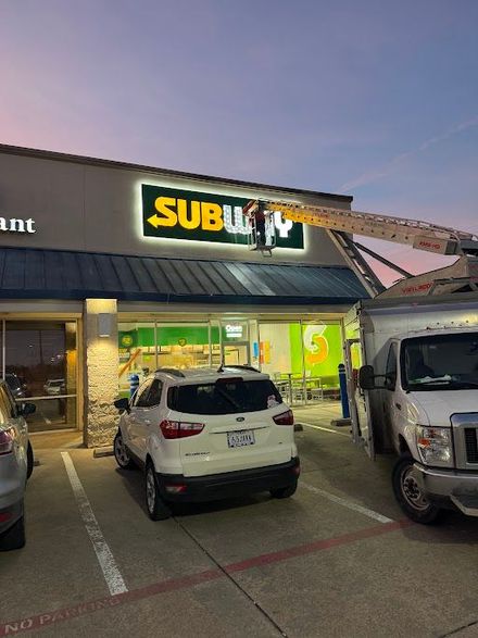 A subway sign is being installed on the side of a building