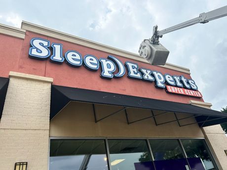 A sign for sleep experts is being installed on the side of a building.