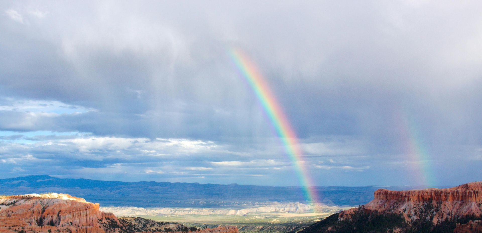 Half a rainbow shooting out from the desert ground straight to the monsoon clouds overhead