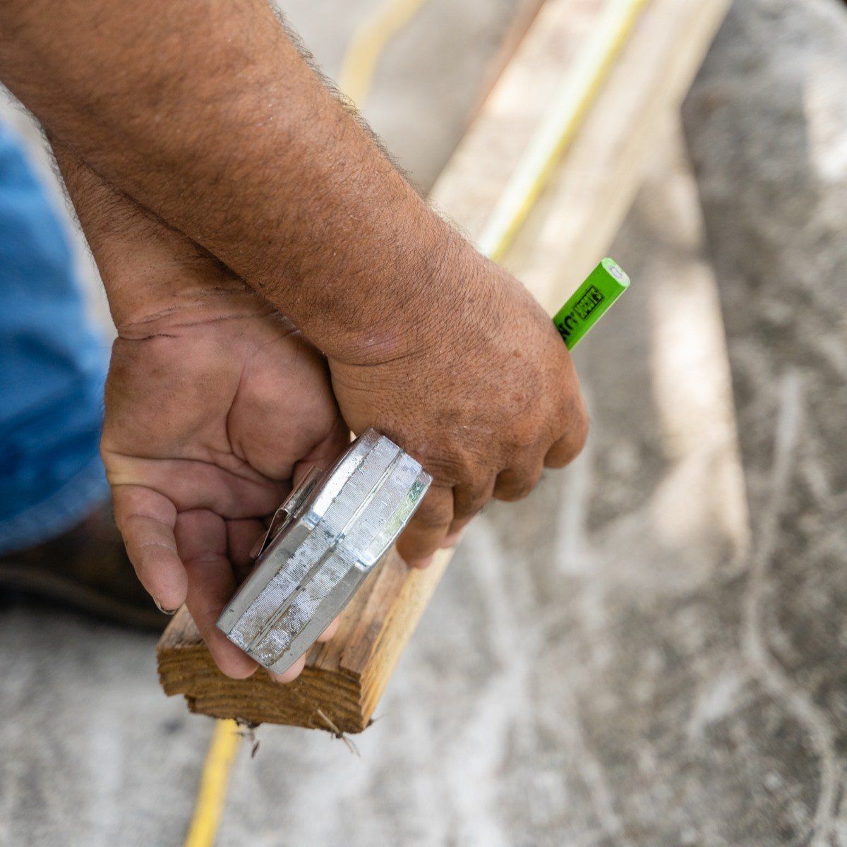 A man is measuring a piece of wood with a tape measure