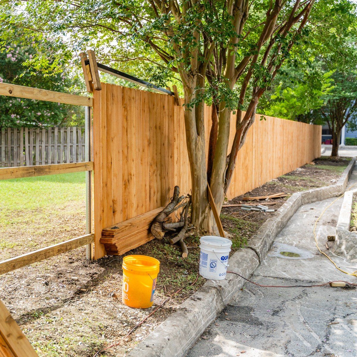 A wooden fence is being built next to a tree.