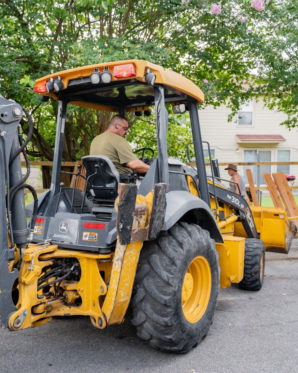 A man is driving a yellow tractor in a parking lot