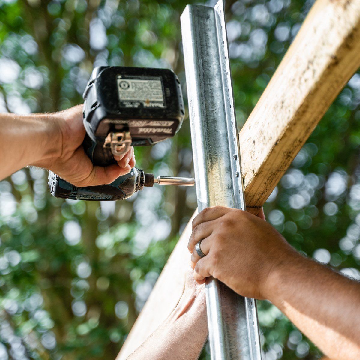 A person is using a drill to drill into a metal pole.