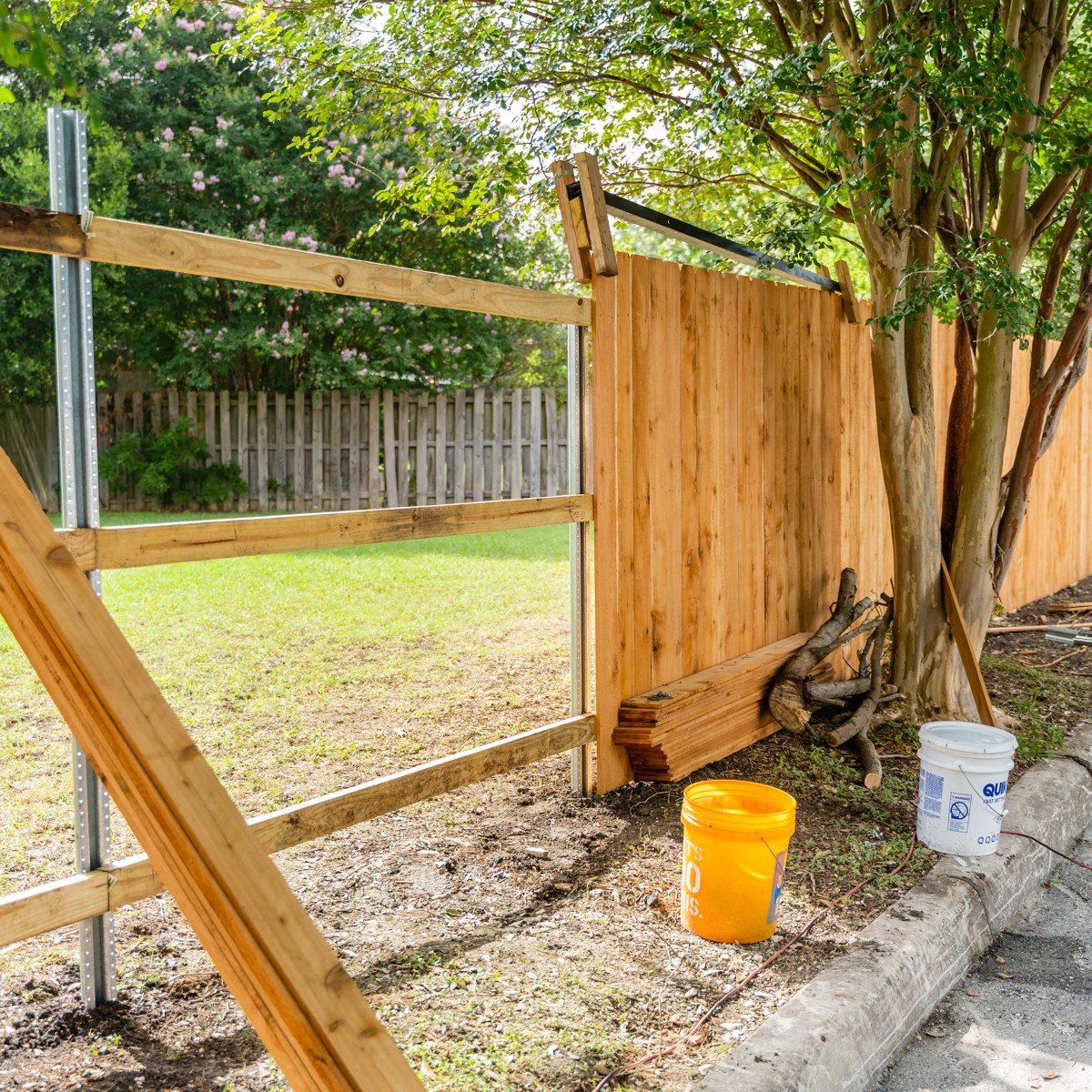 A wooden fence is being built in a backyard.