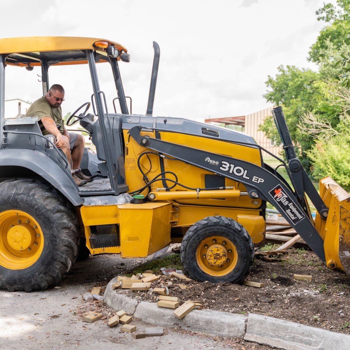 A man is sitting in the driver 's seat of a yellow tractor.