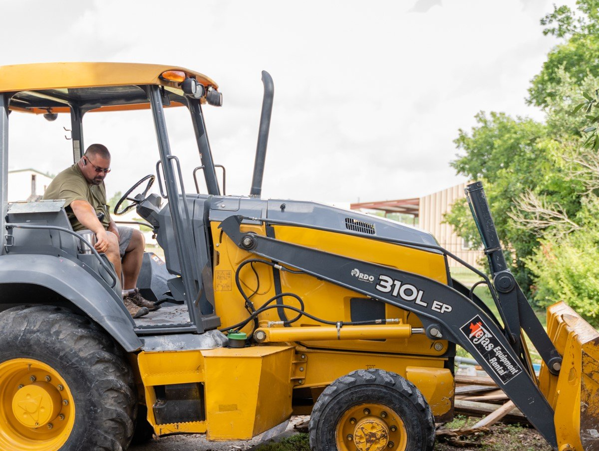 A man is sitting in the driver 's seat of a yellow tractor.