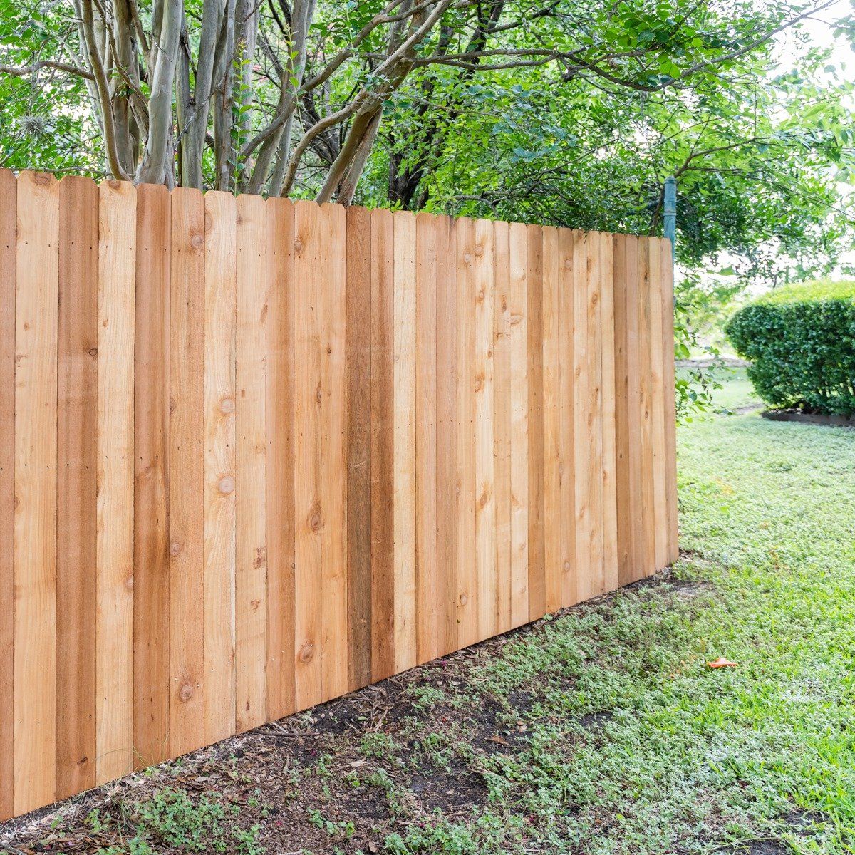 A wooden fence is sitting in the middle of a lush green yard.
