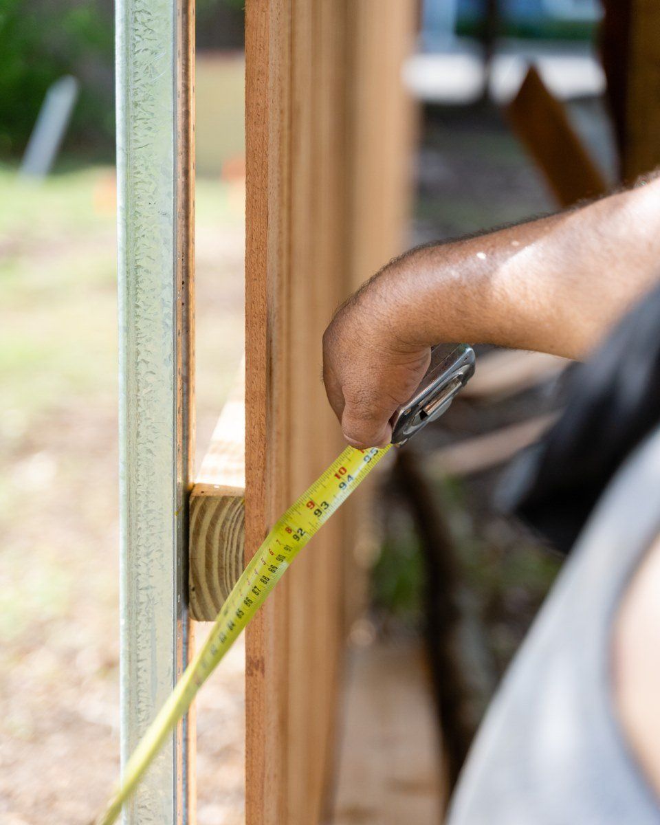 A person is measuring a piece of wood with a tape measure.