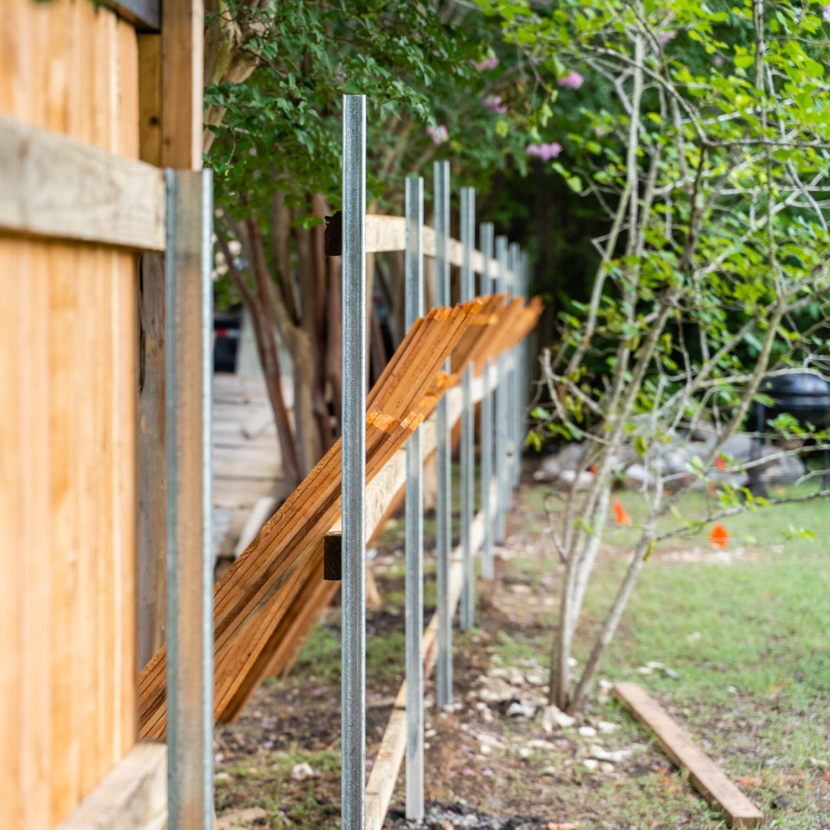 A wooden fence is being built in a backyard.