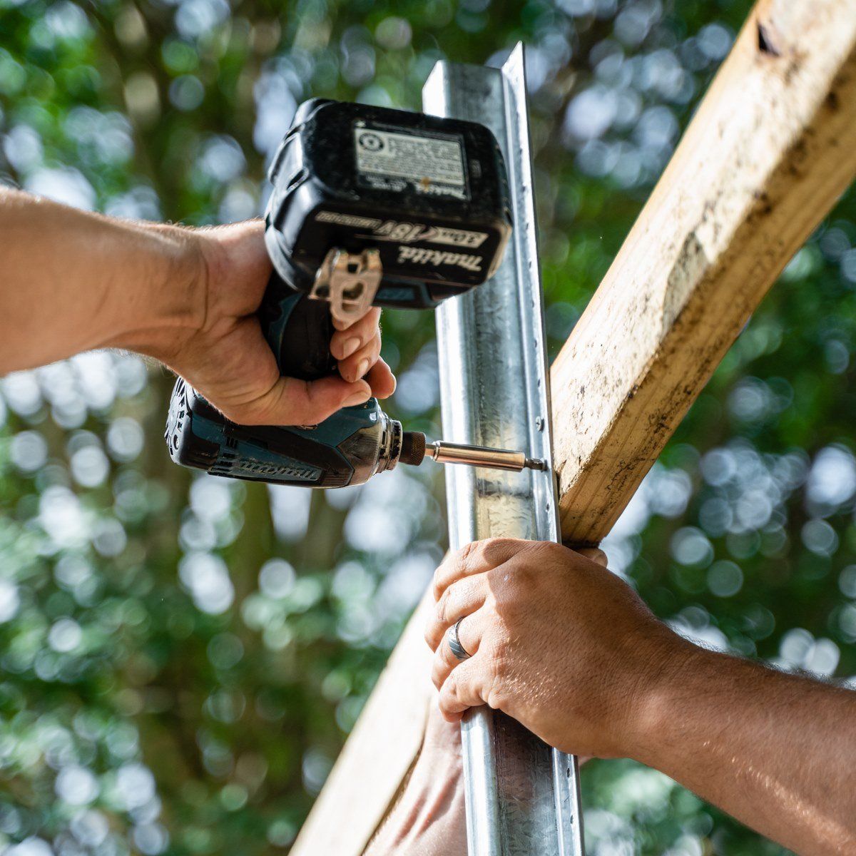 A man is using a makita drill on a piece of wood