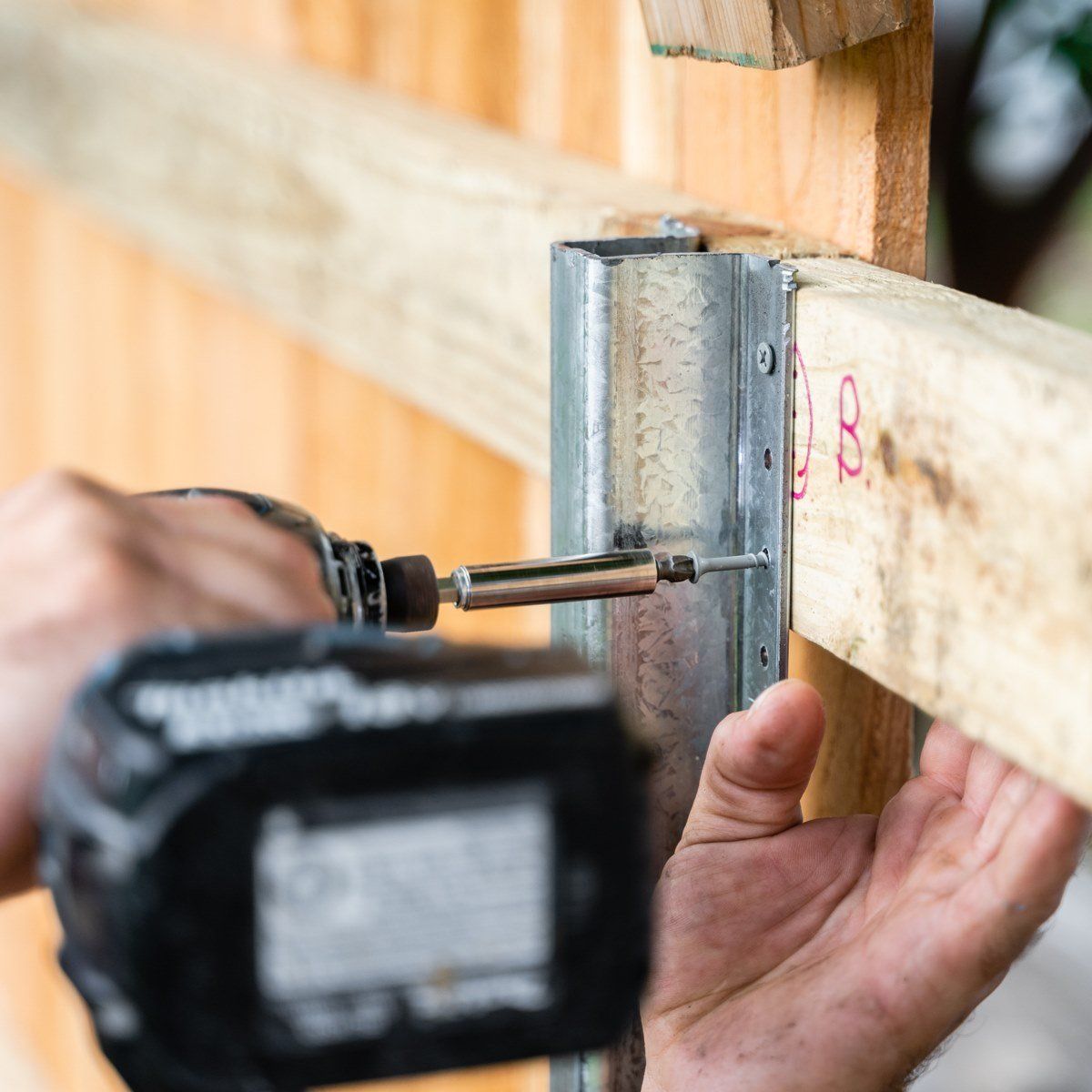 A person is using a makita cordless drill on a piece of wood
