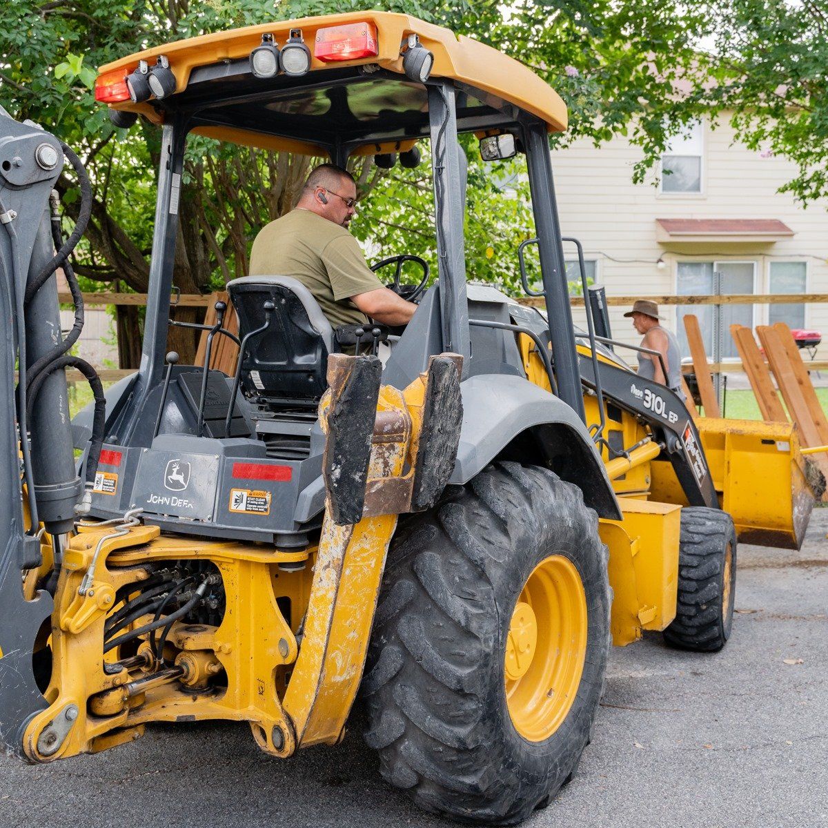 A man is driving a yellow and black tractor