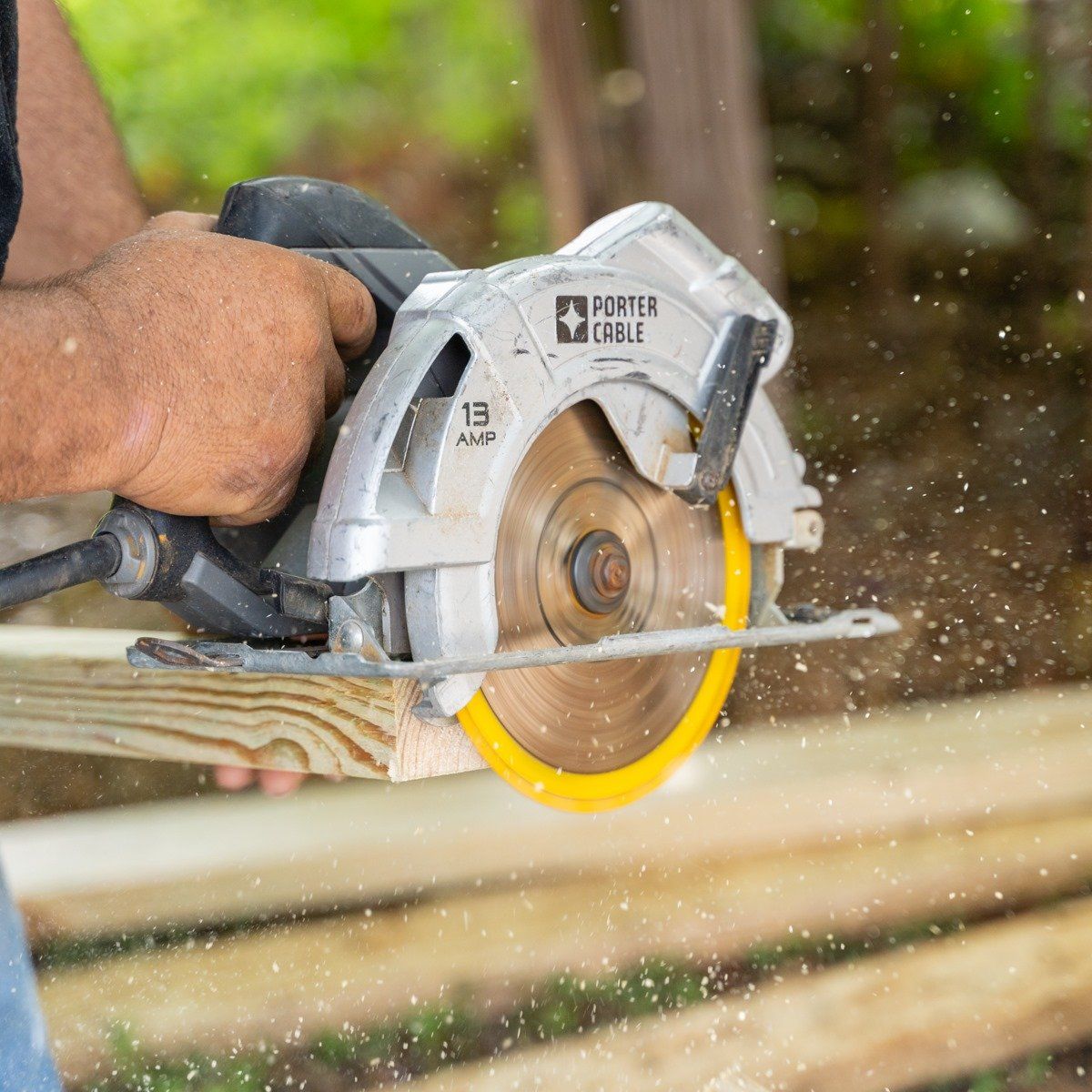 A man is using a circular saw to cut a piece of wood.