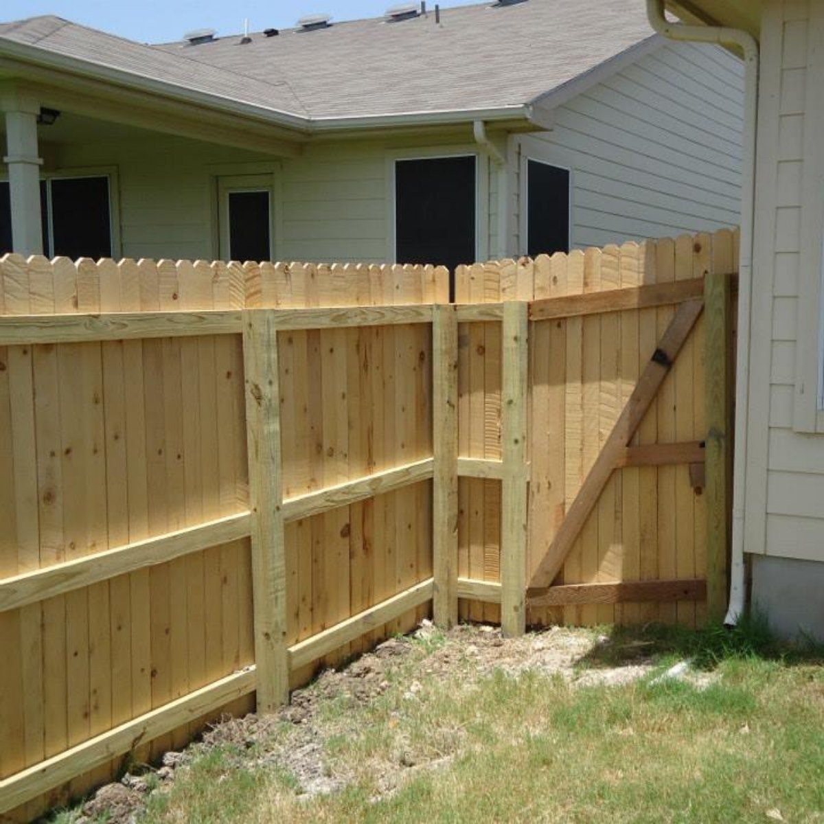 A wooden fence with a gate in front of a house