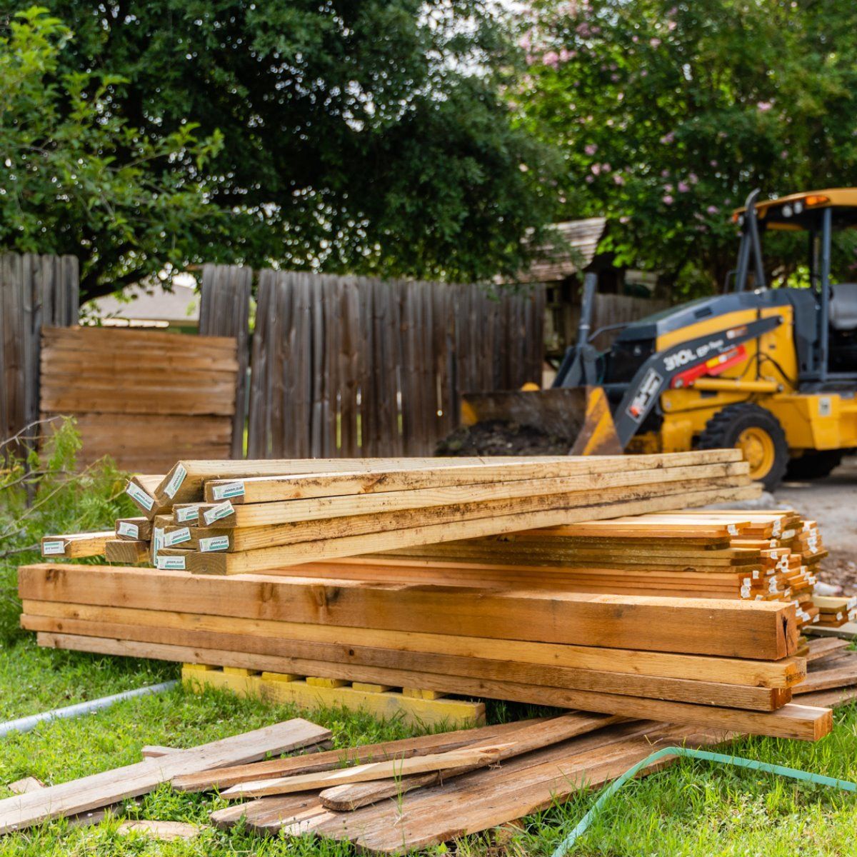 A pile of wood is sitting in the grass next to a tractor.