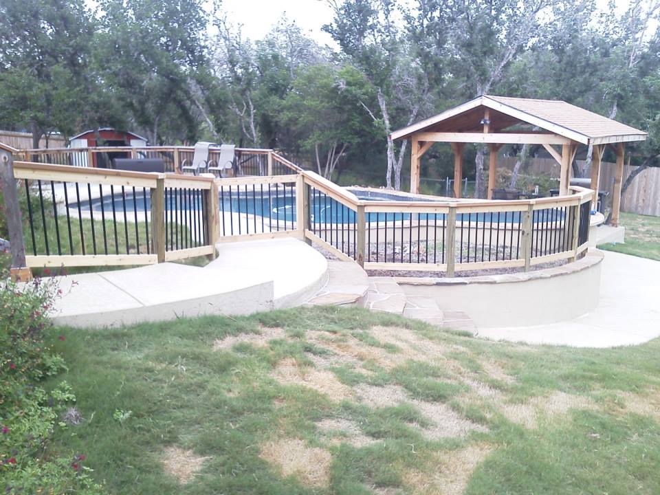 A wooden deck overlooking a swimming pool with a gazebo in the background