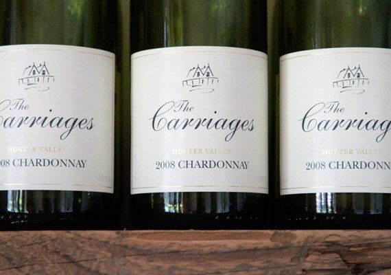 Three bottles of the carriages chardonnay lined up on a wooden shelf