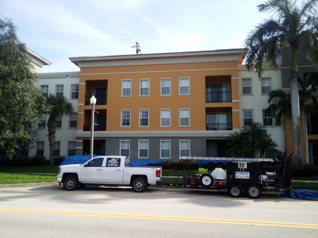 Picture of roof cleaning on an apartment building. You can see RNR Pressure cleaning washing the roof with the company truck parked in front. 