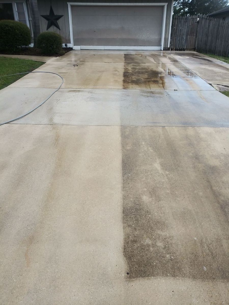 picture showing a driveway that is getting pressure cleaned. You can see the driveway has been half-washed to show the effect pressure washing can have.