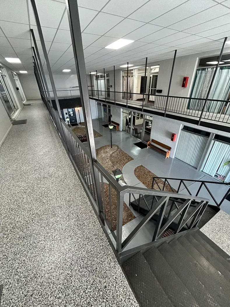 Indoor atrium with a metal staircase, glass railings, and open walkways in a modern building.