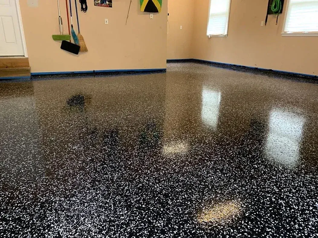 Glossy black speckled flooring in an empty room with beige walls and windows