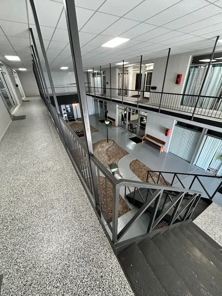 Interior of an office building with a staircase, metal railing, and open mezzanine corridor
