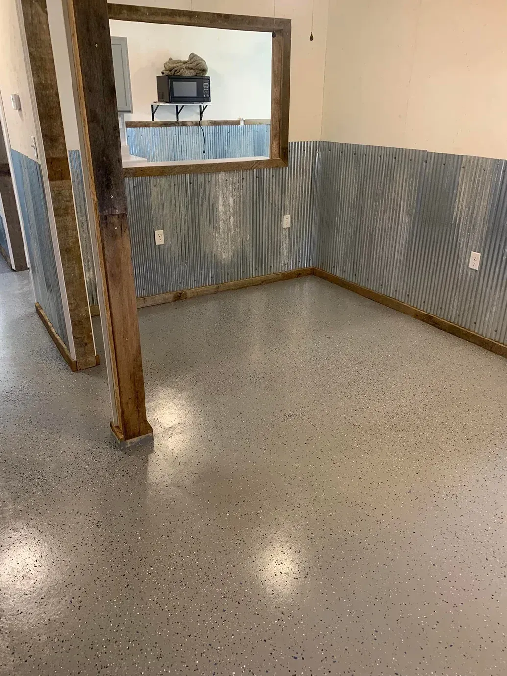 Empty room with speckled floor, wood trim, and blue striped wall paneling