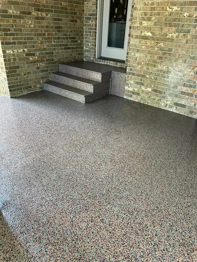 Brick patio with small steps leading to a white door, covered in speckled carpet.