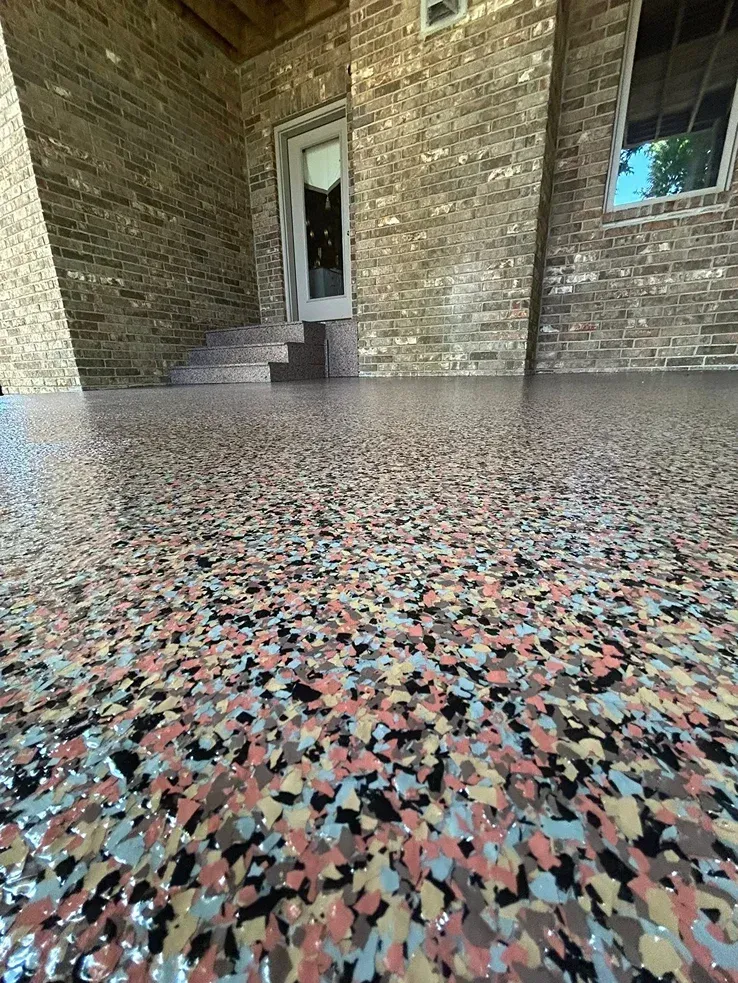 Terrazzo porch floor leading to a brick entryway with a white door and windows.