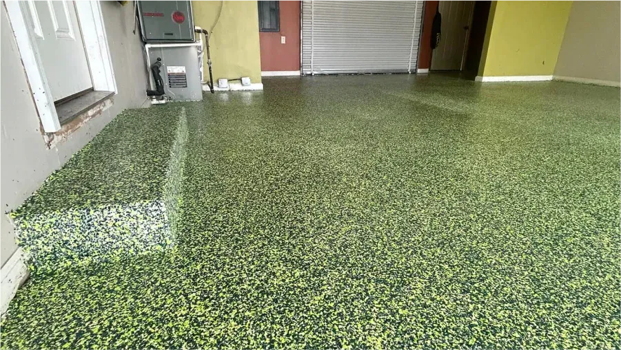 Green and black speckled garage floor with a glossy finish and storage items along the wall.