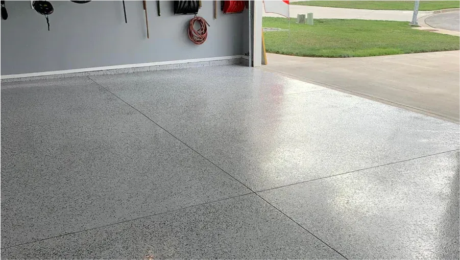Empty speckled concrete garage floor with sunlight near the open doorway
