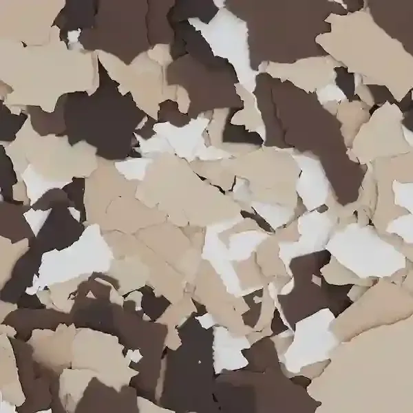 Scattered beige, white, and dark brown paint chips or confetti pieces on a flat surface