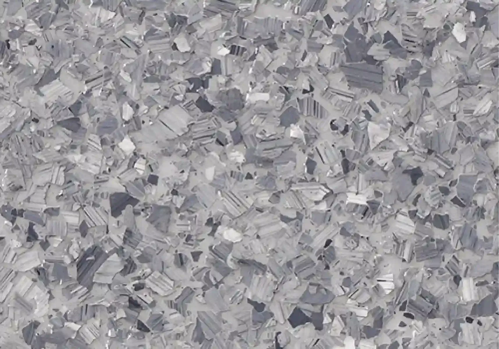 Close-up of a gray, crinkled metallic or paper-textured surface with scattered reflective fragments