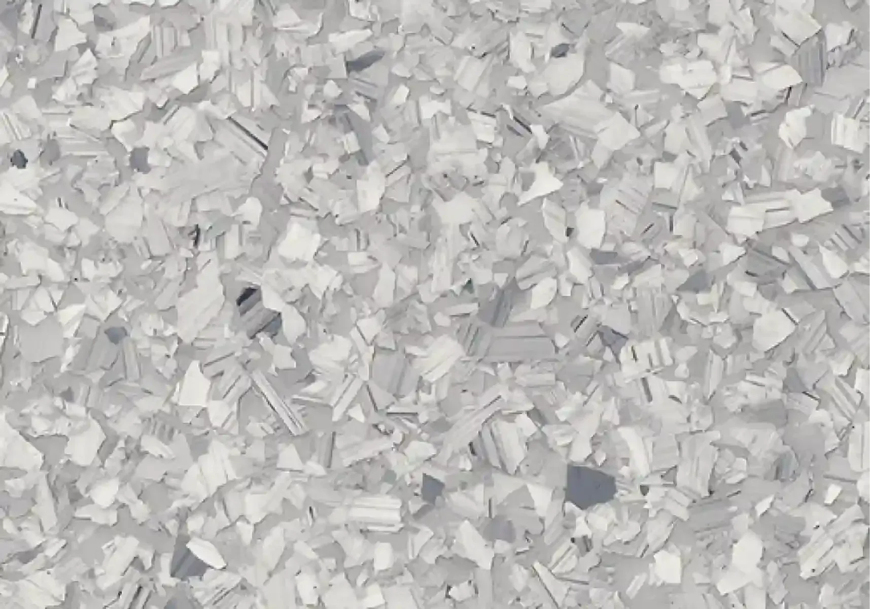 Close-up of scattered white plastic chips on a light gray surface